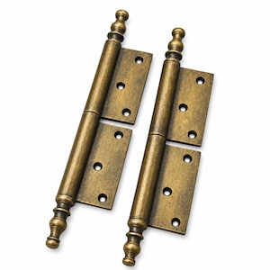 May include: Two antique brass finish door hinges featuring decorative finials at both the top and bottom. Each hinge plate has four pre-drilled screw holes arranged in a vertical pattern, with a central cylindrical barrel connecting the two plates.
