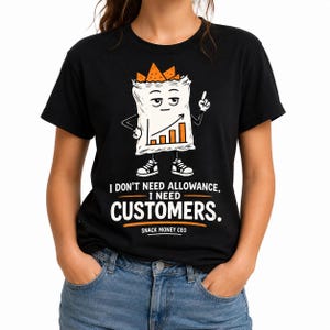 May include: A black t-shirt featuring a graphic of a cartoon snack bag with a face, arms, and legs, displaying an upward trending bar graph. Below the graphic, the text reads: I DON'T NEED ALLOWANCE. I NEED CUSTOMERS. SNACK MONEY CEO.