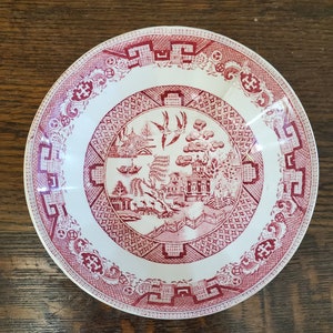 Puede incluir: Un tazón de cerámica blanco con un diseño floral rojo y blanco. El tazón presenta un patrón chino tradicional con un motivo floral rojo sobre un fondo blanco.