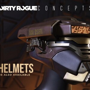 May include: A futuristic helmet with a dark metallic finish, featuring a digital display and intricate mechanical details. The text "FINISHED HELMETS" and "A LIMITED NUMBER ARE ALSO AVAILABLE" are displayed. The helmet is a concept design.
