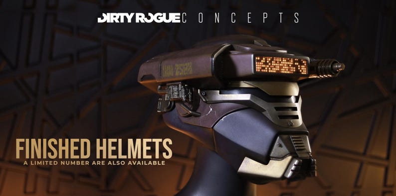 May include: A futuristic helmet with a dark metallic finish, featuring a digital display and intricate mechanical details. The text "FINISHED HELMETS" and "A LIMITED NUMBER ARE ALSO AVAILABLE" are displayed. The helmet is a concept design.