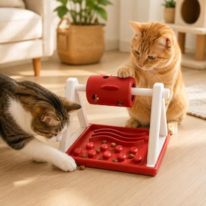 Könnte beinhalten: Ein rot-weißes Futterpuzzle für Katzen aus Kunststoff mit einem rotierenden zylindrischen Leckerli-Spender, der zwischen zwei weißen Stützarmen über einer roten Basis mit erhöhten Rippen und Noppen für langsames Fressen montiert ist.