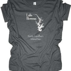 Pu&ograve; includere: T-shirt grigio scuro con grafica bianca del lago Norman, Carolina del Nord. Il testo "Lake Norman" &egrave; sopra il contorno del lago e "North Carolina's -Inland Sea-" sotto. La maglietta &egrave; realizzata in materiale morbido.