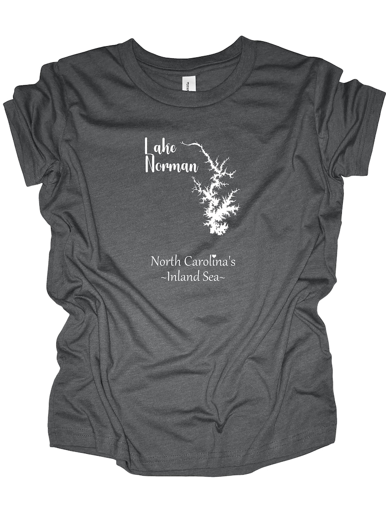 Pu&ograve; includere: T-shirt grigio scuro con grafica bianca del lago Norman, Carolina del Nord. Il testo "Lake Norman" &egrave; sopra il contorno del lago e "North Carolina's -Inland Sea-" sotto. La maglietta &egrave; realizzata in materiale morbido.