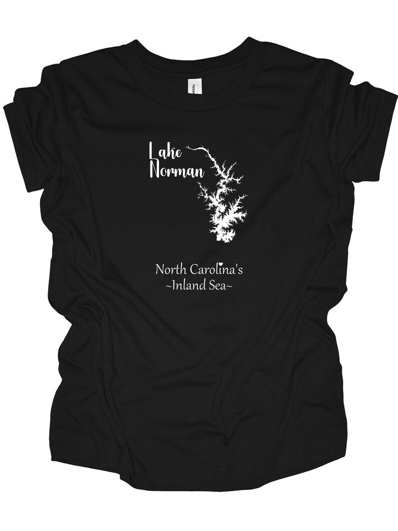 Pu&ograve; includere: T-shirt nera con grafica bianca del lago Norman, Carolina del Nord. La grafica include il contorno del lago e il testo "Lake Norman" sopra e "North Carolina's -Inland Sea-" sotto.