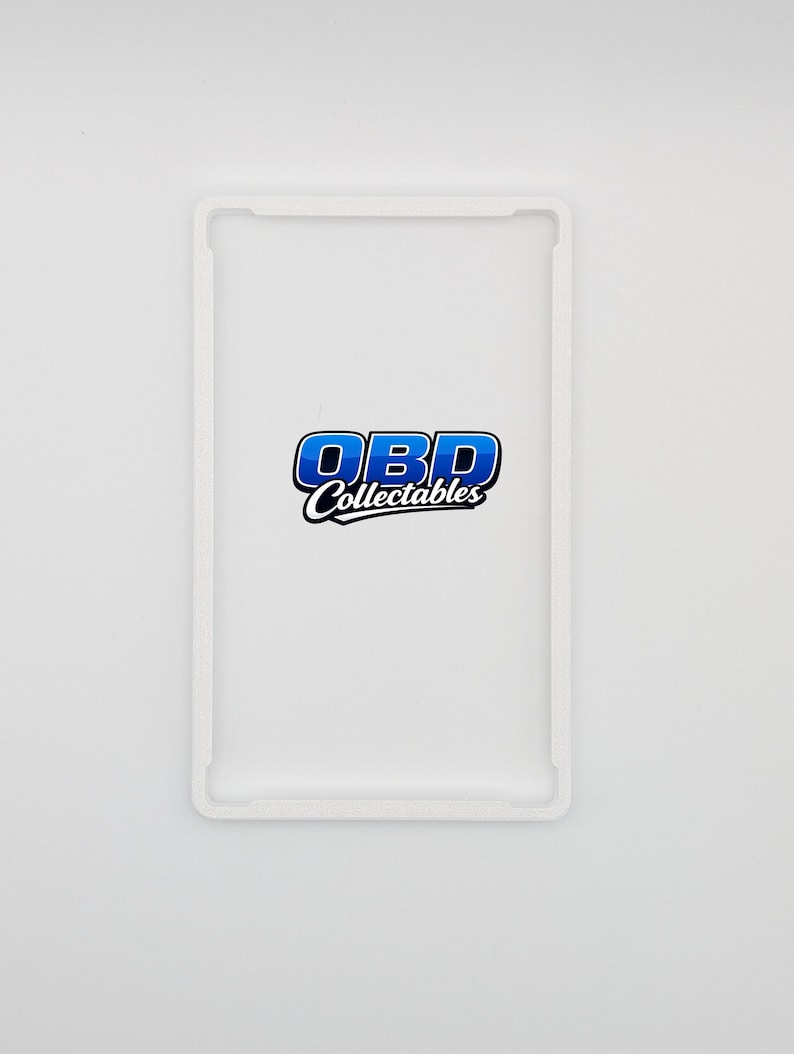 Pu&ograve; includere: Una custodia rettangolare bianca con un logo blu e bianco che recita "OBD Collectables". La custodia ha un bordo rialzato ed &egrave; posta su uno sfondo bianco. Il logo &egrave; in un carattere stilizzato.