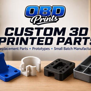 May include: A collection of four custom 3D printed parts in blue, white, black, and gray. The text OBD Prints CUSTOM 3D PRINTED PARTS Replacement Parts • Prototypes • Small Batch Manufacturing is displayed above the objects on a wooden surface.