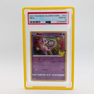 Pu&ograve; includere: Una carta Pok&eacute;mon Mew del set 2021 Pok&eacute;mon Celebrations, valutata e presentata in un supporto giallo. Il testo recita "2021 POKEMON CELEBRATIONS #011 MEW GEM MT 10". L'artwork della carta mostra Mew rosa.