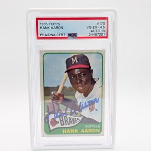 Pu&ograve; includere: Una carta di baseball Hank Aaron Topps del 1965, valutata VG-EX+ 4.5, con Auto 10, in un supporto protettivo. La carta mostra Hank Aaron in uniforme dei Braves, con una mazza. Oggetto da collezione.