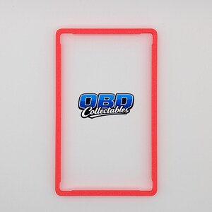 Pu&ograve; includere: Un porta carte rettangolare rosso con angoli arrotondati. Il supporto ha un centro trasparente e il testo "OBD Collectables" in blu e bianco. Il supporto &egrave; progettato per proteggere ed esporre carte collezionabili.