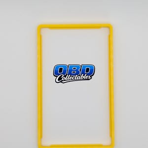 Pu&ograve; includere: Una cornice rettangolare gialla con angoli arrotondati. La cornice circonda uno sfondo bianco con il testo "OBD Collectables" in blu e bianco. La cornice &egrave; di un colore giallo brillante.