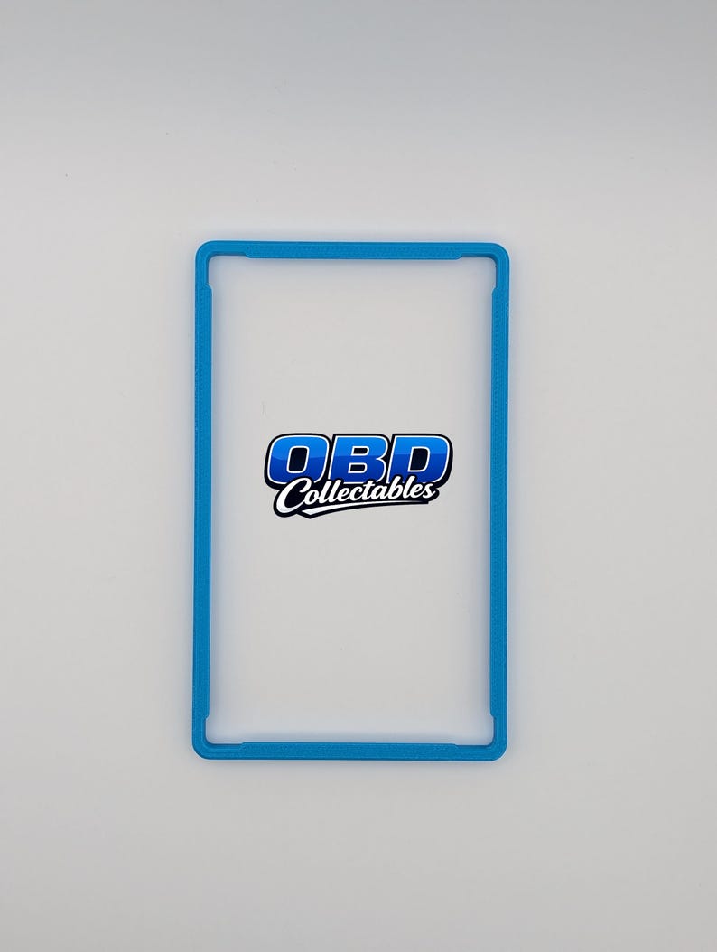 Pu&ograve; includere: Una cornice rettangolare blu chiaro con angoli arrotondati. La cornice circonda un interno bianco. Il testo "OBD Collectables" &egrave; visualizzato al centro della cornice in blu e bianco.