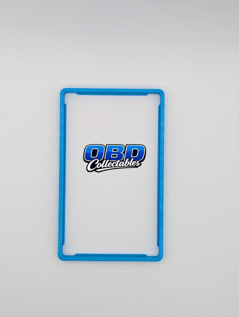 Pu&ograve; includere: Una vetrina rettangolare in plastica trasparente con un bordo blu brillante. Il testo "OBD Collectables" &egrave; visualizzato in un logo blu e bianco al centro della vetrina. La vetrina &egrave; progettata per contenere e proteggere oggetti da collezione.