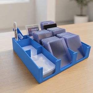 Peut inclure: Un organisateur de rangement en plastique bleu avec plusieurs compartiments contenant des piles de pochettes de protection transparentes pour cartes. Un marqueur Sharpie blanc et un outil OBD bleu sont placés dans les fentes prévues à gauche.