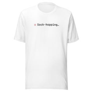 May include: White t-shirt with a crew neck. The shirt features the text "* Sock-hopping..." in a small, centered font. The asterisk is a light pink color.