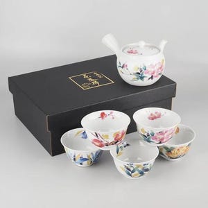 Op de afbeelding: Een set van drie keramische mokken met een gespikkelde, matte afwerking. De mokken zijn in de kleuren crème, lichtgrijs en donkergrijs. Elke mok heeft een eenvoudig, minimalistisch ontwerp en een afgeronde handgreep.
