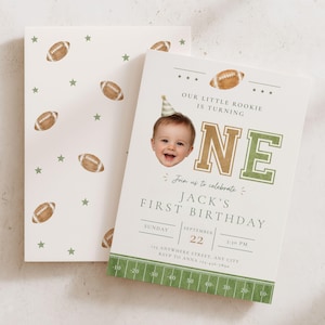May include: A first birthday invitation card featuring a football theme with a photo of a child in a party hat, the text "OUR LITTLE ROOKIE IS TURNING ONE", "JACK'S FIRST BIRTHDAY", and a green football field graphic at the bottom with a matching envelope.