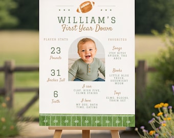 May include: A white milestone birthday sign featuring a football theme with the text William's First Year Down, a photo of a baby, player stats including 23 pounds and 31 inches tall, favorites, and a green football field yard line graphic.