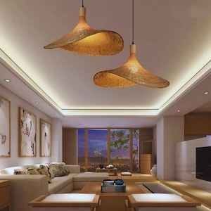 May include: Two woven pendant lights with a wide, hat-like shape hang from the ceiling. The lamps are made of a light brown material, likely rattan or wicker, and have a warm, inviting glow. The room has a modern design.