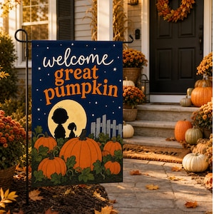 May include: A rectangular garden flag featuring a dark blue night sky background with white stars and a yellow moon. The text reads "welcome great pumpkin" in white and orange. Below, black silhouettes of two figures stand near orange pumpkins.