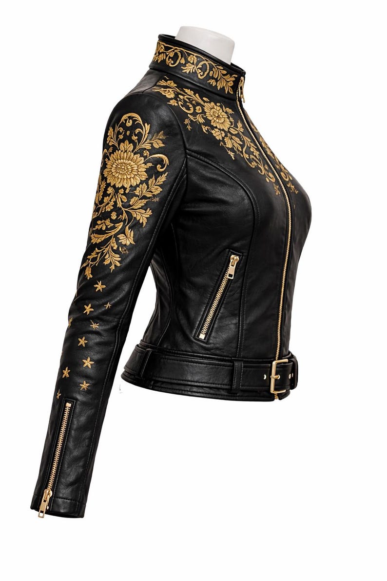 May include: Black leather jacket with gold floral embroidery. It has a high collar, zip front, and a waist belt. The sleeves are decorated with gold stars. The jacket is made of leather.