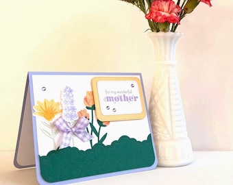 May include: A handmade greeting card with a floral design and the text "for my wonderful mother." The card features a scalloped green border, a purple bow, and a vase of red and purple flowers.