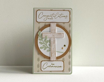 May include: A First Communion card featuring a wooden cross, olive branch, and the words "Congratulations on your" and "First Communion." The card has a light green and brown colour scheme with a decorative leaf pattern.