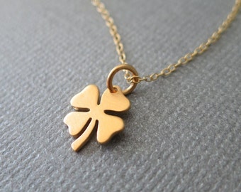 May include: A gold chain necklace with a small four-leaf clover pendant.