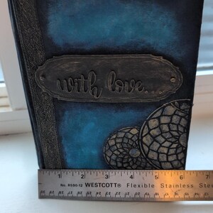 Peut inclure: Un journal fait à la main avec une couverture bleu foncé et une plaque métallique décorative avec l'inscription "with love...". Le journal présente un motif attrape-rêves et mesure environ 15 cm de long.
