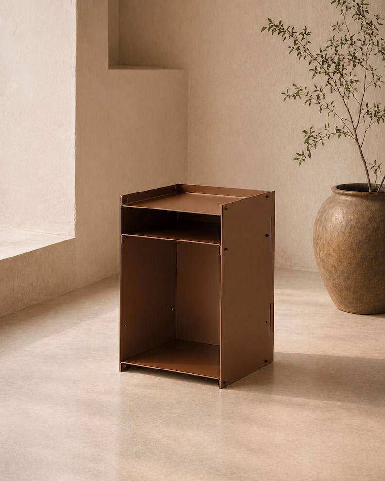 May include: A matte brown metal side table featuring a rectangular top surface with raised edges, a single open storage shelf below, and a large open compartment at the base. The structure is held together by visible screws on the side panels.