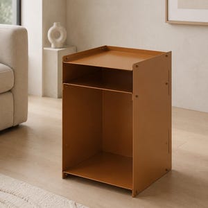 May include: A mustard-colored metal side table featuring a rectangular top surface with raised edges, a single open storage shelf below, and a large open compartment at the base. The structure is held together by visible screws on the side panels.