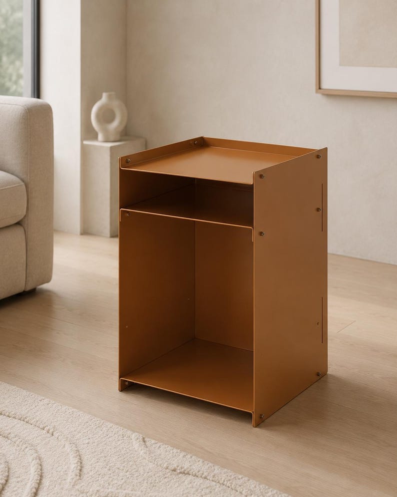 May include: A mustard-colored metal side table featuring a rectangular top surface with raised edges, a single open storage shelf below, and a large open compartment at the base. The structure is held together by visible screws on the side panels.