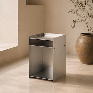May include: A rectangular metal side table constructed from brushed silver-toned panels. The piece features a flat top surface, an open middle shelf, and a larger open storage compartment at the base, all held together by visible metal fasteners.