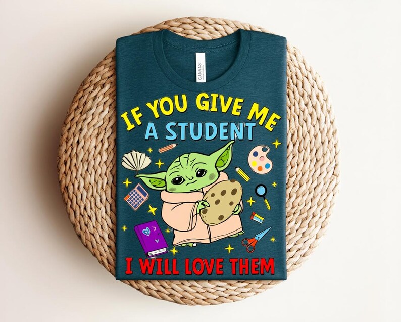 May include: Teal t-shirt featuring a cartoon Yoda-like character holding a cookie, surrounded by school supplies. Text reads "IF YOU GIVE ME A STUDENT I WILL LOVE THEM" in yellow and red. A fun design for teachers.