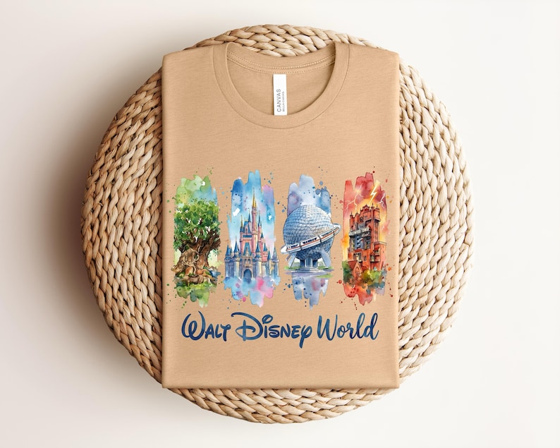 May include: Tan t-shirt featuring a watercolor design of Walt Disney World landmarks. The design includes the Tree of Life, Cinderella Castle, Spaceship Earth, and the Tower of Terror, with "Walt Disney World" written below.