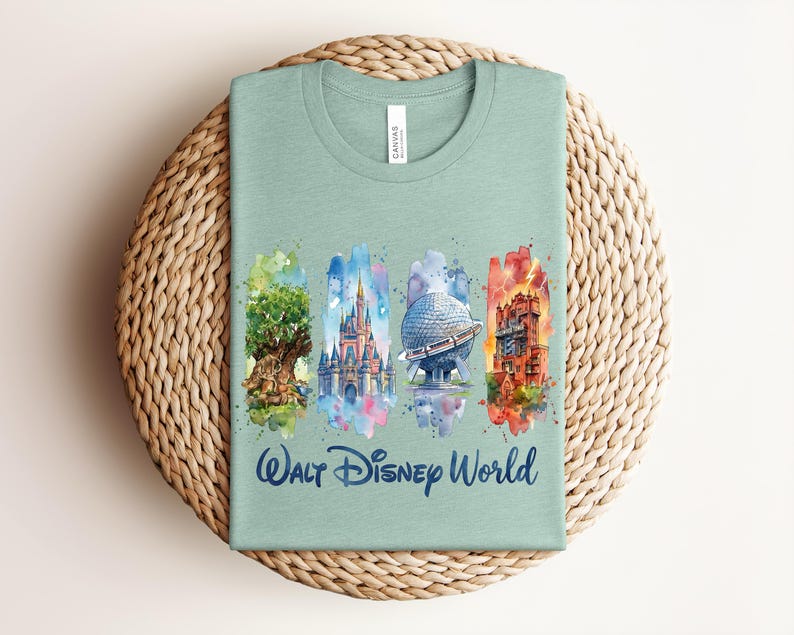 May include: A light green t-shirt featuring a watercolor design of Walt Disney World landmarks. The design includes the Tree of Life, Cinderella Castle, Spaceship Earth, and the Tower of Terror. The words "Walt Disney World" are printed in blue.