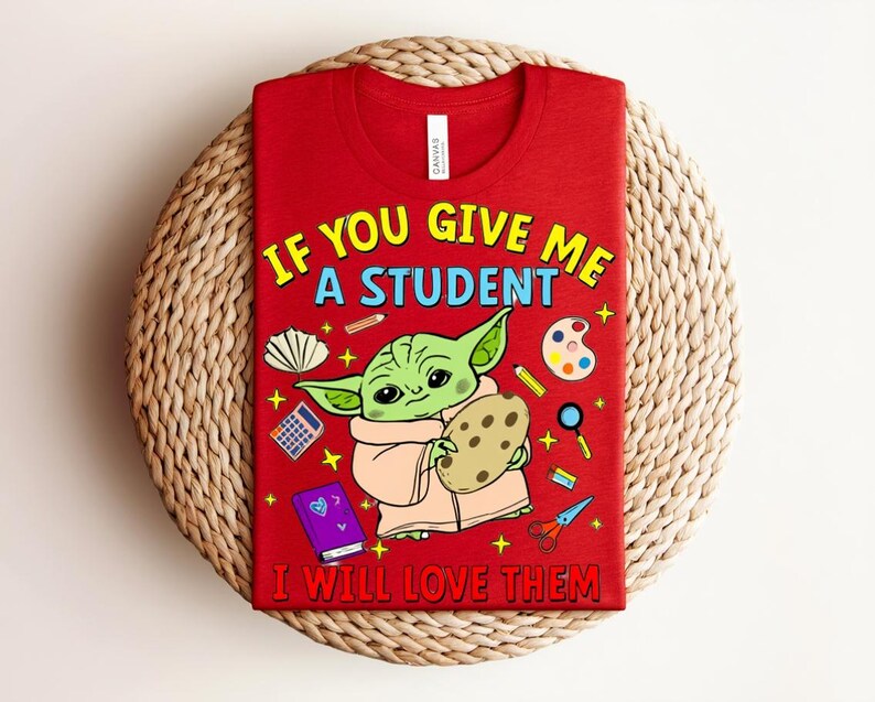 May include: Red t-shirt with the text "IF YOU GIVE ME A STUDENT I WILL LOVE THEM" and a cartoon character holding a cookie. The design includes school-themed illustrations like pencils, a calculator, and scissors.