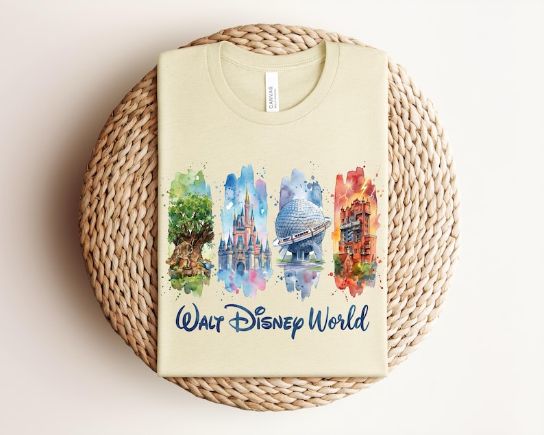 May include: A light beige t-shirt featuring watercolor illustrations of iconic Walt Disney World landmarks. The design includes the Tree of Life, Cinderella Castle, Spaceship Earth, and the Tower of Terror, with "Walt Disney World" text.