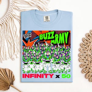 Puede incluir: Camiseta azul claro con un gr&aacute;fico de Buzz Lightyear y el texto "BUZZ ARMY" en verde, con "INFINITY x 50" en rojo y verde. El gr&aacute;fico incluye m&uacute;ltiples figuras de Buzz Lightyear en verde y blanco.