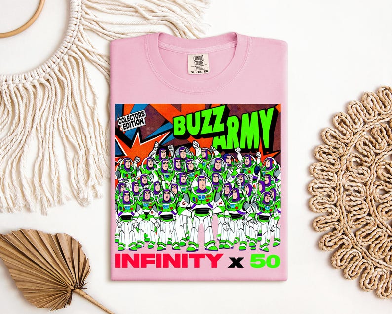 Puede incluir: Una camiseta rosa claro con un gr&aacute;fico de Buzz Lightyear y el texto "BUZZ ARMY" en verde y naranja. El gr&aacute;fico incluye m&uacute;ltiples figuras de Buzz Lightyear. El texto "INFINITY x 50" tambi&eacute;n se muestra en rosa y verde.