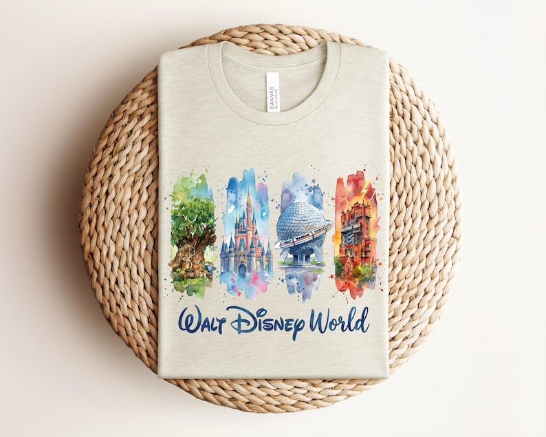 May include: A light beige t-shirt featuring a watercolor design of Walt Disney World landmarks. The design includes the Tree of Life, Cinderella Castle, Spaceship Earth, and the Tower of Terror, with the words "Walt Disney World" in blue.