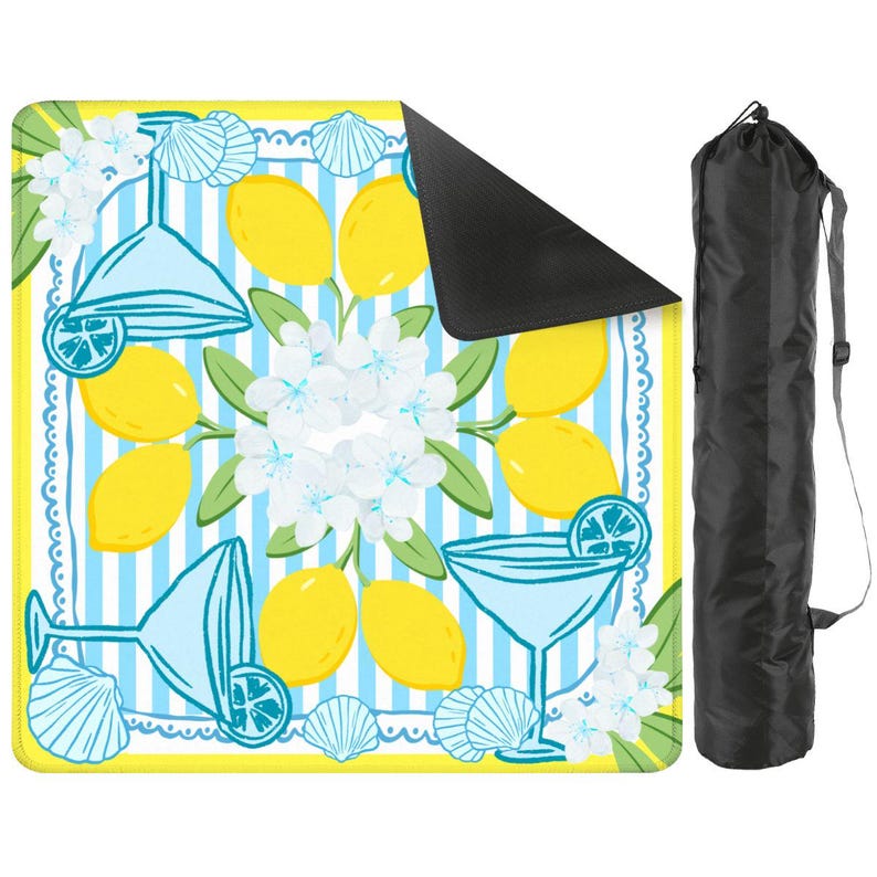May include: A square picnic blanket with a lemon and cocktail design. The blanket features yellow lemons, blue cocktail glasses, white flowers, and seashells on a blue and white striped background. A black carrying bag is included.