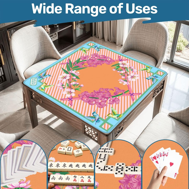 May include: A square game table mat featuring an orange center with a pink floral wreath and hummingbird pattern, bordered by diagonal orange and white stripes and a light blue frame. The mat is displayed with playing cards and mahjong tiles.