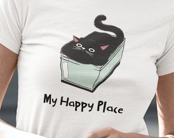 May include: White t-shirt featuring a cartoon black cat in a box with the text "My Happy Place" in black. The cat has pink ears and is in a light blue box. The shirt is short-sleeved.