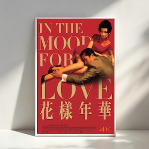May include: A rectangular movie poster with a vibrant red background featuring a man and a woman in a close embrace. The text IN THE MOOD FOR LOVE is printed in large gold letters, with Chinese characters below and the text A FILM BY WONG KAR WAI 4K.