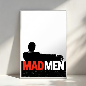 May include: A rectangular poster featuring a black silhouette of a person sitting and holding a cigarette against a white background. The text MAD MEN is printed in bold red and white letters over a black base with a grid of small white dots.