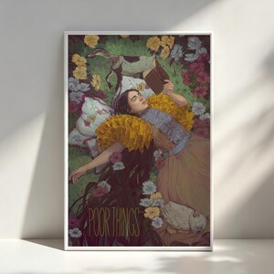 May include: A framed art print featuring a person lying in a field of flowers, reading a book. The person is wearing a yellow ruffled collar and a long dress. A dog and a bird are also in the scene. The words "POOR THINGS" are printed at the bottom.