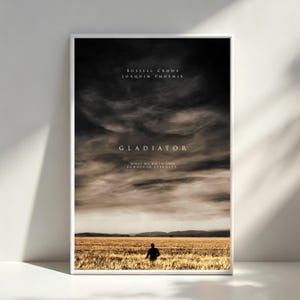 Könnte beinhalten: Gerahmtes Filmplakat für "Gladiator" mit Russell Crowe und Joaquin Phoenix. Das Poster zeigt einen dramatischen Himmel über einem Feld mit einer einzelnen Figur. Der Titel "Gladiator" und der Slogan sind sichtbar.