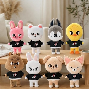 May include: Nine plush animal dolls in various designs, including a pig, bear, wolf, duck, squirrel, rabbit, dog, and fox. Each doll wears a black shirt with a red and white graphic. The dolls are soft and cuddly, perfect for children.