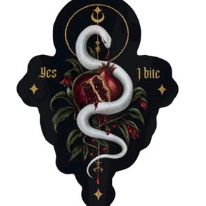 May include: A die-cut sticker featuring a white snake coiled around a split pomegranate with red seeds. The design includes green leaves, a gold crescent moon, and vertical line symbols. The text 'Yes' and 'I bite' appears in gold lettering.